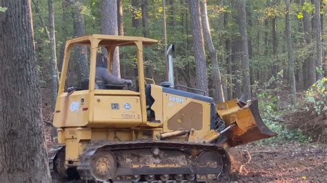 clearing trees with mini excavator|bulldozer knocking down trees.